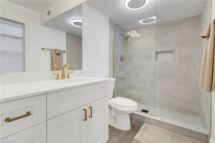 Bathroom featuring a walk in shower, visible vents, vanity, and wood finished floors