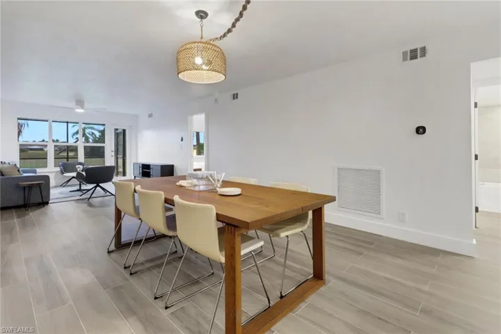 Dining space with wood tiled floor, visible vents, ceiling fan, and baseboards