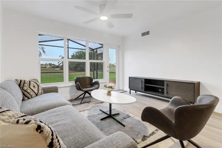 Living room featuring light wood-style floors, baseboards, visible vents, and a ceiling fan