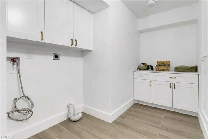 Laundry area featuring cabinet space, baseboards, wood finish floors, washer hookup, and electric dryer hookup