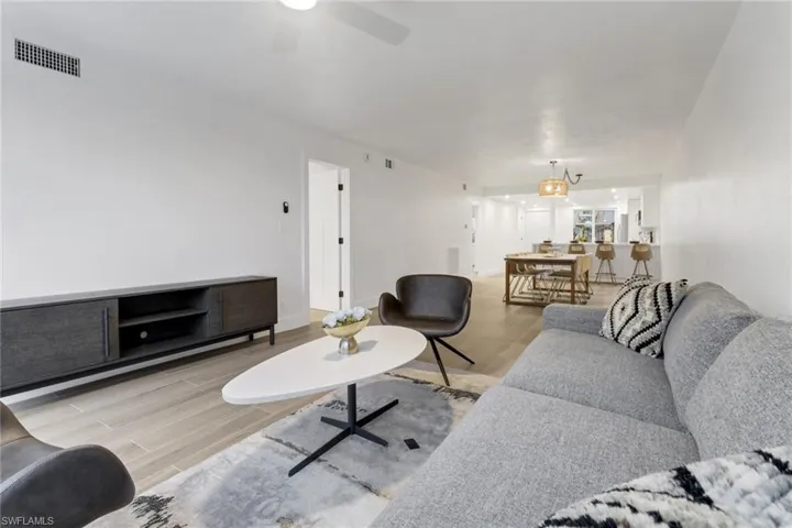 Living area with light wood-type flooring, visible vents, ceiling fan, and baseboards