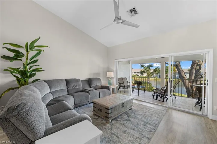 Living room with vaulted ceiling, a water view, and a ceiling fan
