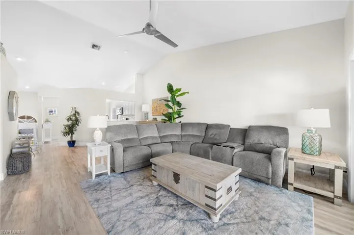 Living room with ceiling fan, vaulted ceiling, and LTV flooring