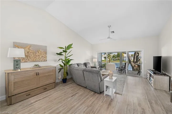 Living room featuring ceiling fan, light hardwood / wood-style floors, and vaulted ceiling