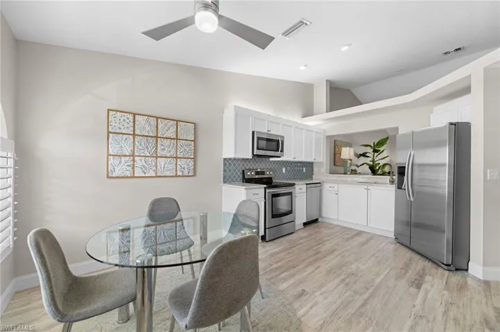 Kitchen with decorative backsplash, appliances with stainless steel finishes, ceiling fan, white cabinetry, and lofted ceiling
