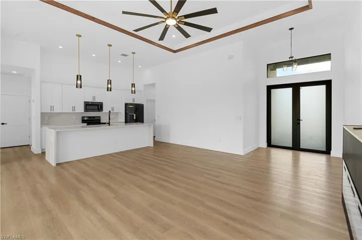 Unfurnished living room featuring a high ceiling, light wood finished floors, a ceiling fan, and recessed lighting