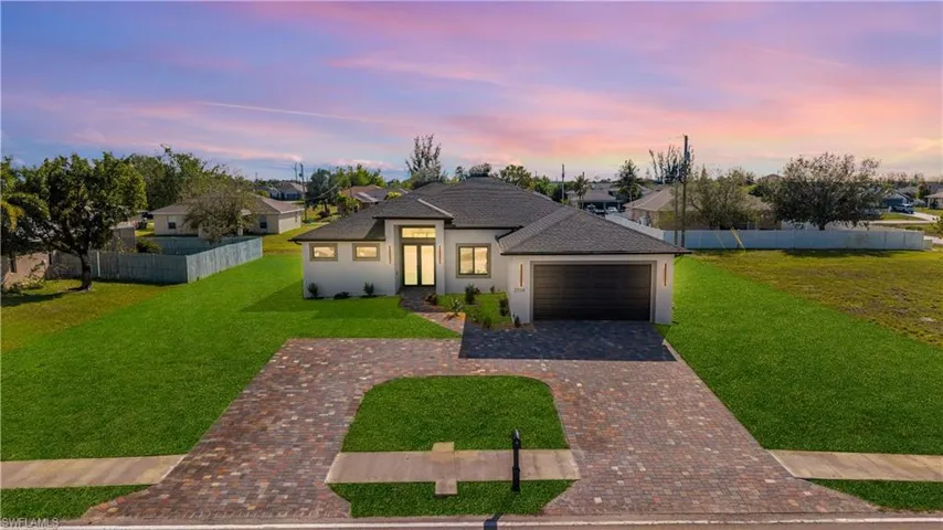 View of front of property featuring decorative driveway, stucco siding, an attached garage, a residential view, and roof with shingles