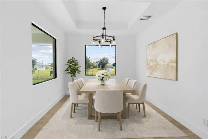 Dining area with light wood-style floors, a tray ceiling, and hanging lights