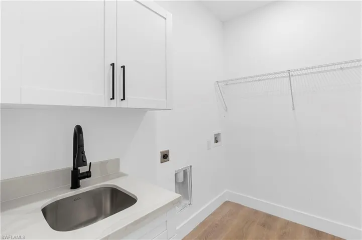 Laundry room with light wood-style flooring, electric dryer hookup, hookup for a washing machine, and cabinet space