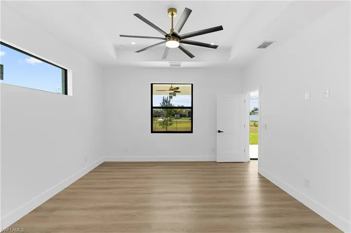 Empty room featuring healthy amount of natural light, light wood-style flooring, a tray ceiling, and recessed lighting