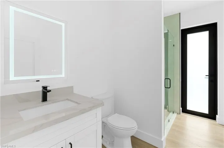 Bathroom featuring a stall shower, vanity, and light wood-type flooring