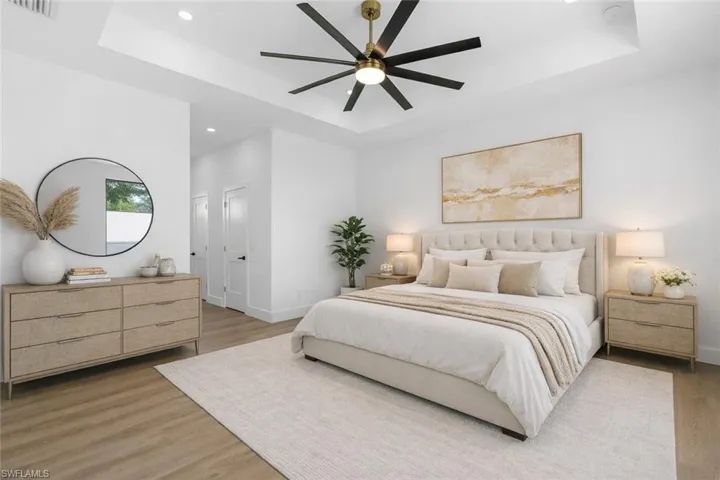 Bedroom with a tray ceiling, a ceiling fan, light wood-style floors, and recessed lighting