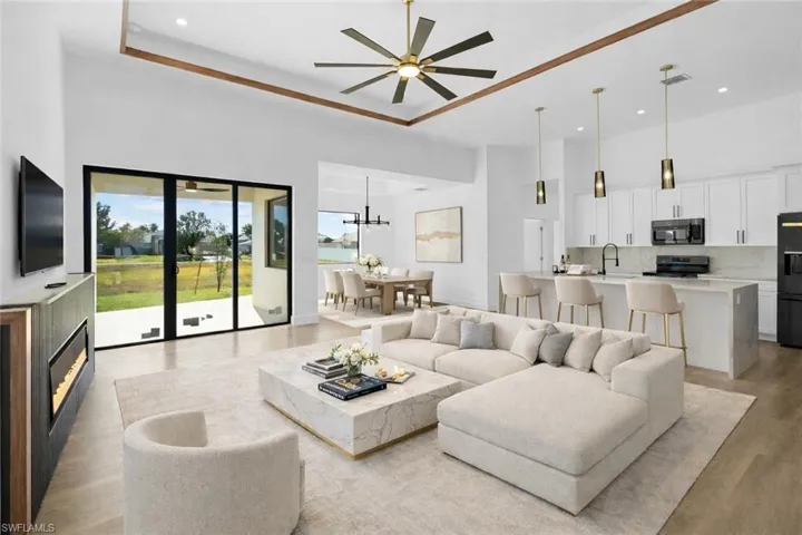 Living room with a high ceiling, light wood finished floors, a ceiling fan, and recessed lighting