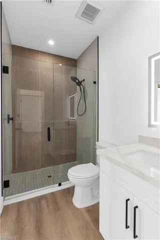 Bathroom with a shower stall, vanity, and light wood-type flooring