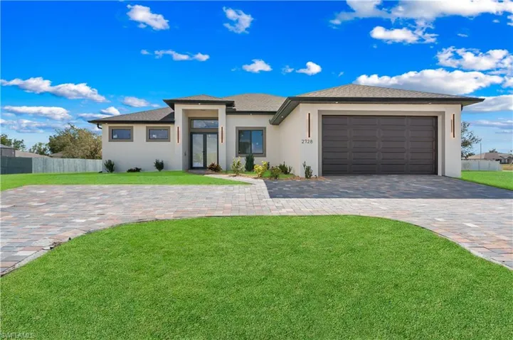 Prairie-style house with stucco siding, decorative driveway, an attached garage, roof with shingles, and french doors