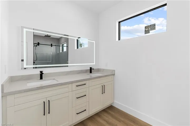Full bathroom featuring a shower, double vanity, and light wood-style flooring