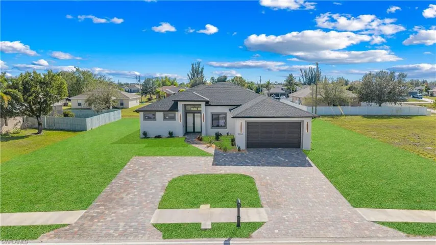 View of front of property with a residential view, decorative driveway, stucco siding, and an attached garage