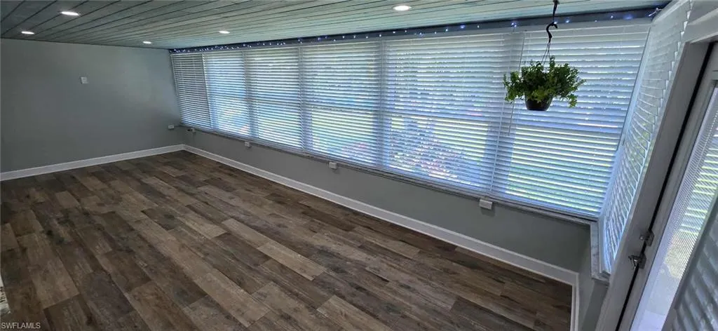 Unfurnished room with recessed lighting, a healthy amount of sunlight, baseboards, and dark wood-style floors