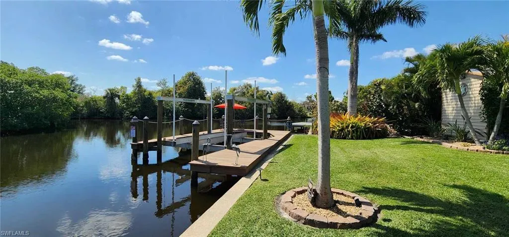 Dock area featuring a lawn, a water view, and boat lift