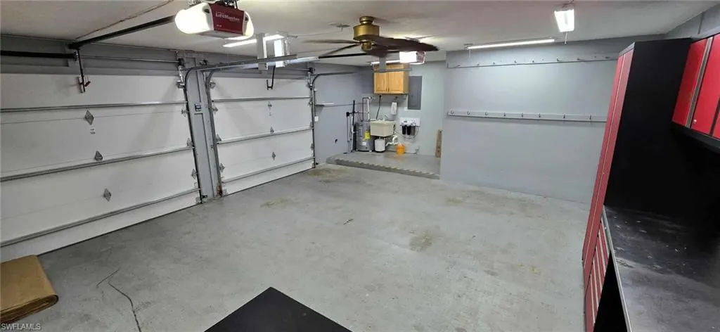Garage with electric panel, ceiling fan, a sink, and a garage door opener