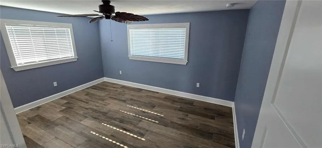 Unfurnished room with ceiling fan, baseboards, and wood finished floors