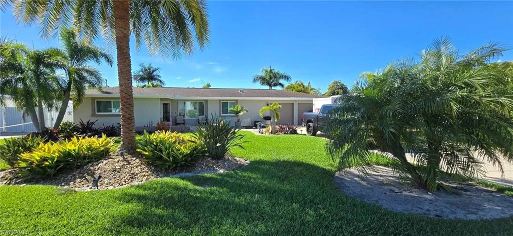 View of front of house with an attached garage, stucco siding, fence, and a front yard
