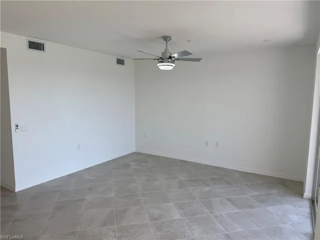 Spacious interior featuring neutral tone tile flooring, a modern ceiling fan with integrated lighting, recessed lighting, white baseboards, and a large sliding door opening to the exterior