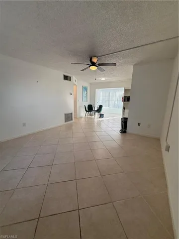 Empty room featuring ceiling fan, a textured ceiling, and light tile patterned flooring