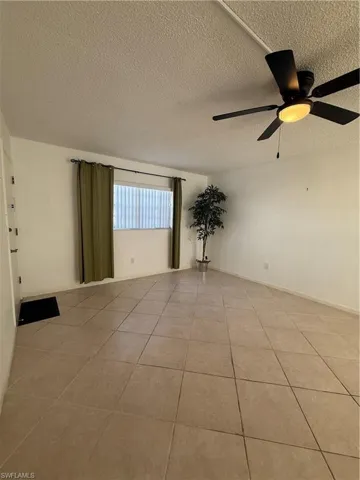 Tiled spare room with a textured ceiling and a ceiling fan