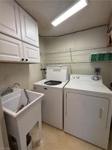 Laundry area featuring cabinet space, washing machine and dryer, and a textured ceiling