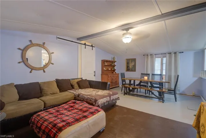 Living room with concrete floors, ceiling fan, and lofted ceiling with beams