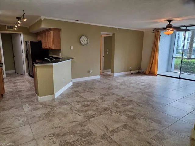 Kitchen with dark countertops, a peninsula, wood finish cabinets, a ceiling fan, and ornamental molding