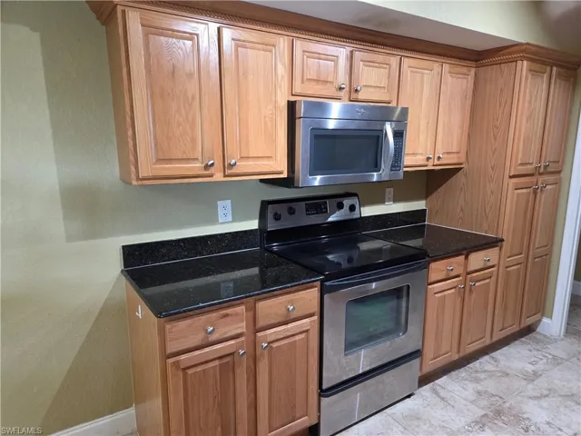 Kitchen featuring stainless steel appliances, dark stone counters, and wood finish cabinets