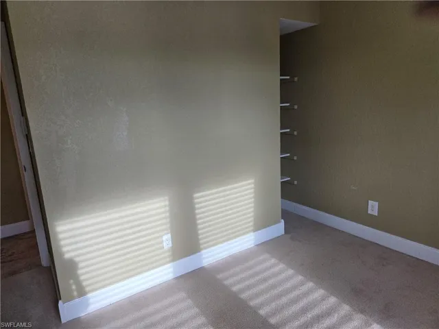 Empty room featuring baseboards and carpet flooring