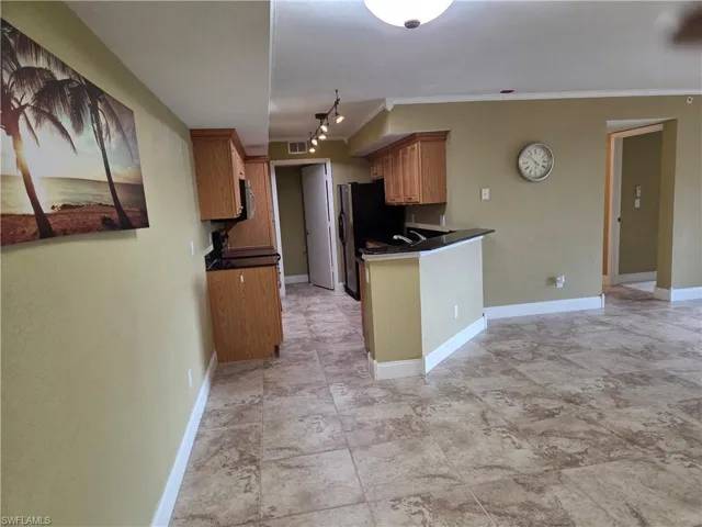 Kitchen featuring dark countertops, wood finish cabinetry, ornamental molding, and a peninsula