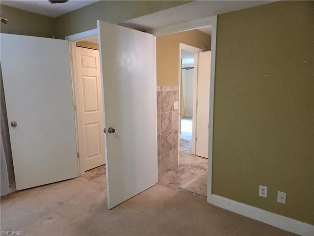 Corridor featuring light colored carpet, tile walls, and wainscoting