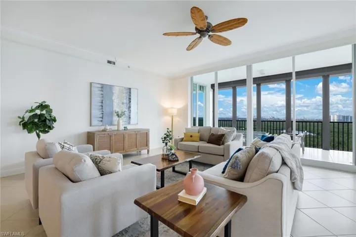 Tiled living room with ceiling fan, a healthy amount of sunlight, and ornamental molding