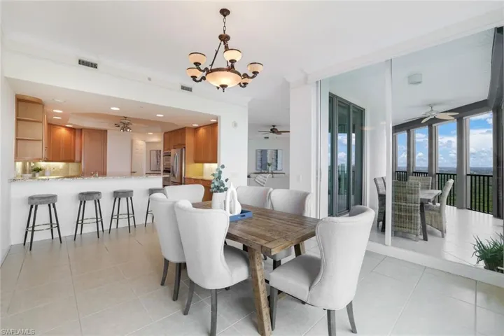 Dining space featuring ornamental molding, light tile patterned flooring, and ceiling fan with notable chandelier