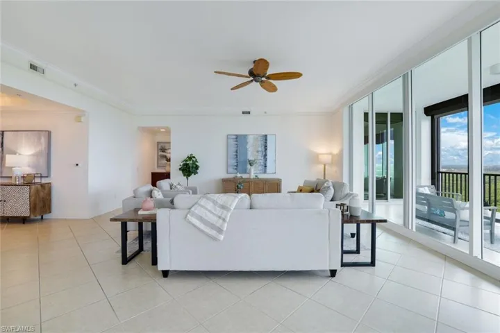 Living room featuring ornamental molding, ceiling fan, and light tile patterned floors