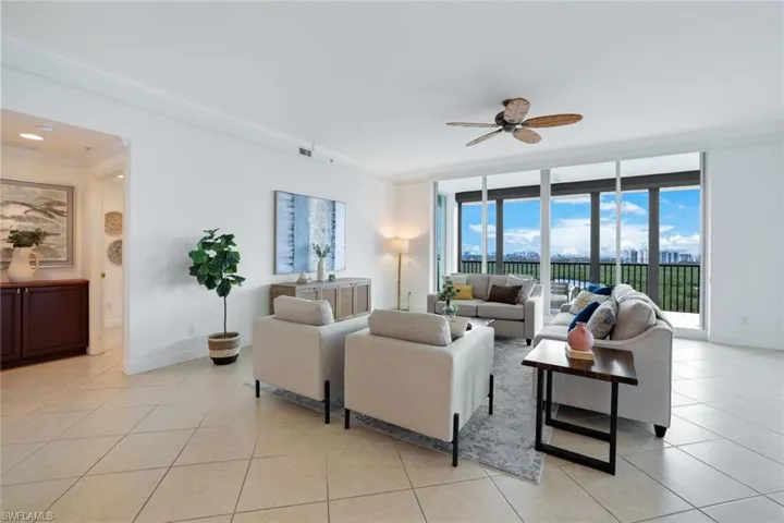 Living room featuring ornamental molding, a wall of windows, ceiling fan, and light tile patterned floors