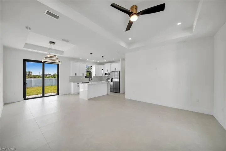 Unfurnished living room featuring a raised ceiling and ceiling fan