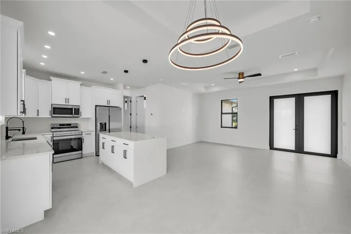 Kitchen featuring sink, a tray ceiling, stainless steel appliances, and a center island