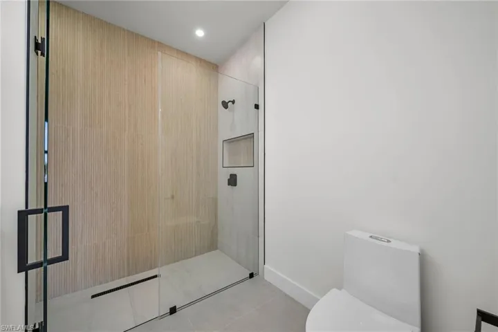 Bathroom with tile patterned flooring, toilet, and a shower