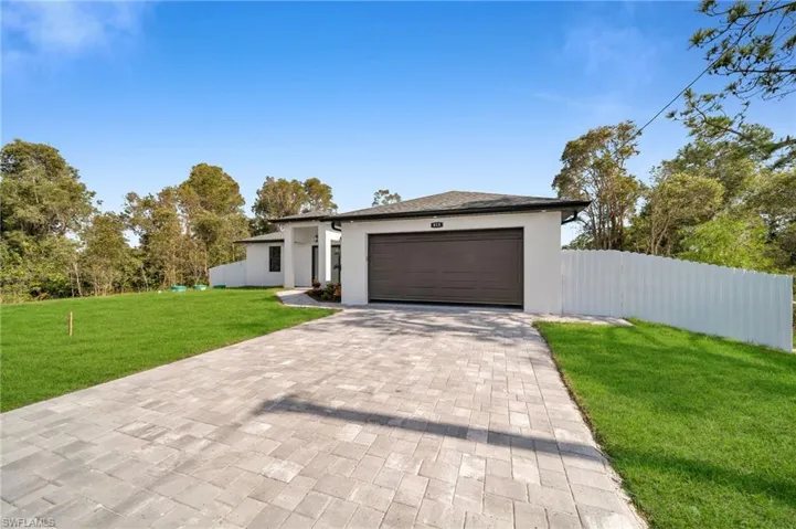 View of front of home with a garage and a front lawn