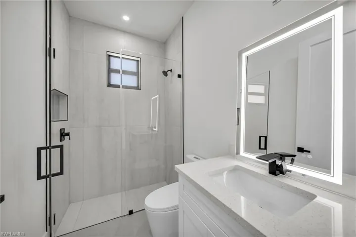 Bathroom featuring vanity, tile patterned floors, toilet, and walk in shower