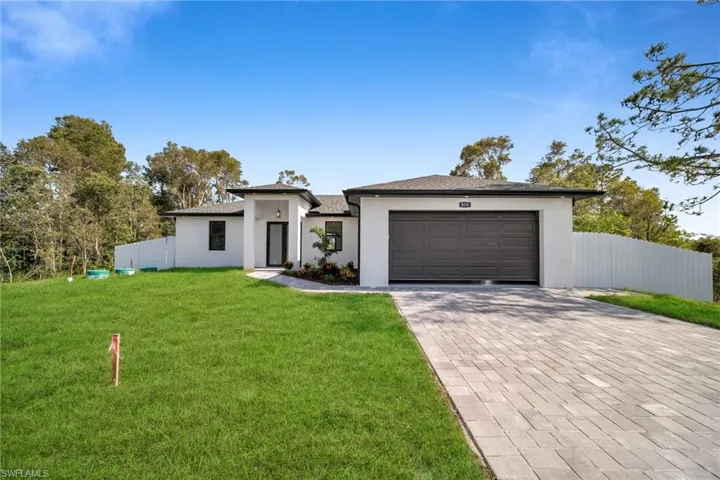 View of front of property with a garage and a front lawn