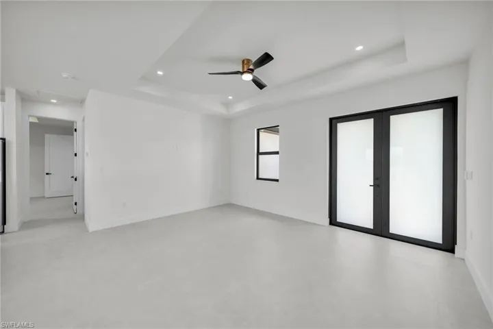 Spare room with a raised ceiling, ceiling fan, and french doors
