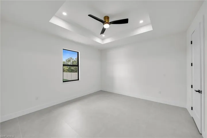 Empty room featuring ceiling fan and a raised ceiling