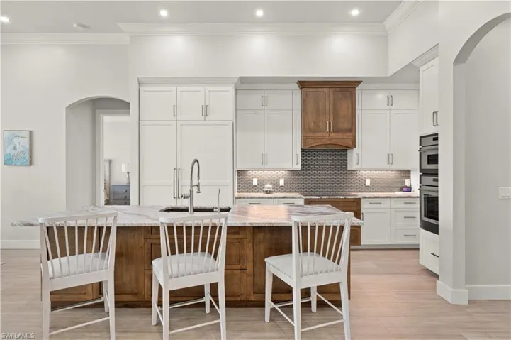 Gourmet kitchen with a large central island featuring a stone countertop and rich wood-toned base cabinetry