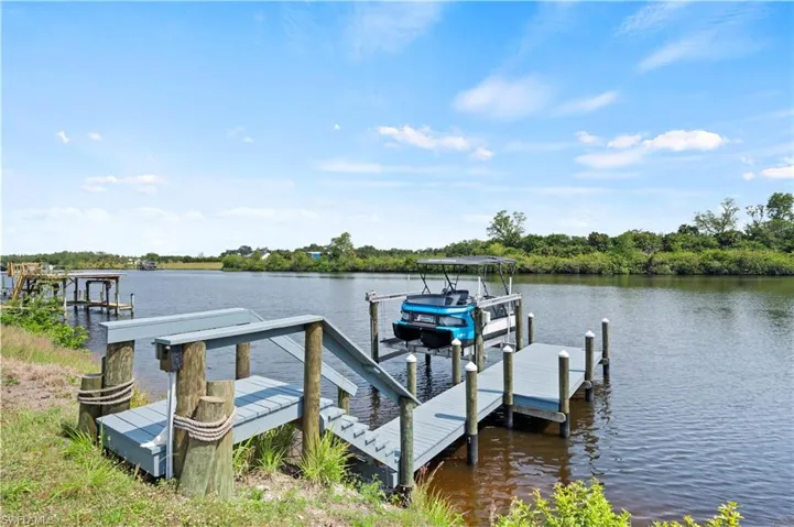 Waterfront property featuring a private boat dock with stairs, a boat lift, and additional pilings